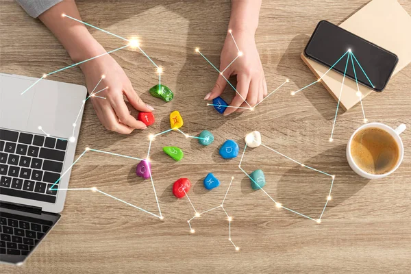 Top view of astrologer holding stones with zodiac sign beside laptop, coffee and constellations — Stock Photo