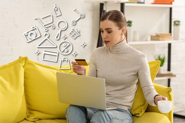 Muchacha atractiva con tarjeta de crédito y café usando el ordenador portátil cerca de la ilustración - foto de stock
