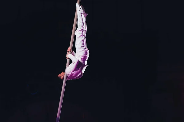 KYIV, UCRANIA - 1 DE NOVIEMBRE DE 2019: Vista lateral de gimnasta de aire flexible realizando con poste en circo aislado en negro - foto de stock