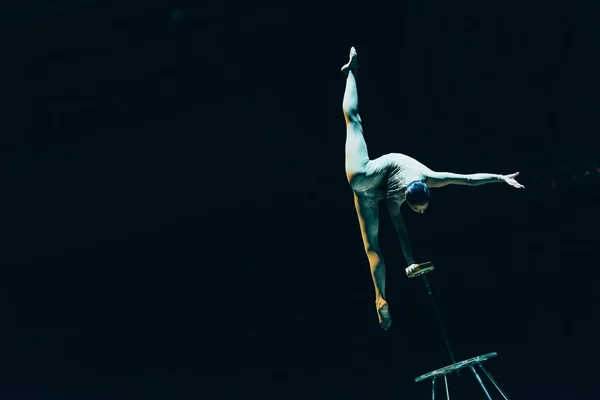 KYIV, UKRAINE - NOVEMBER 1, 2019: Gymnast doing split and handstand in circus isolated on black — Stock Photo