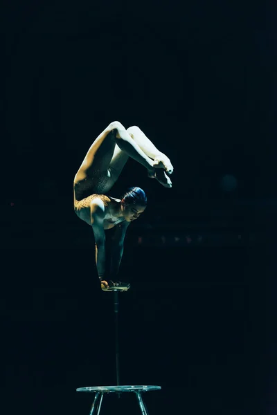 KYIV, UKRAINE - NOVEMBER 1, 2019: Female acrobat performing exercise in circus isolated on black — Stock Photo
