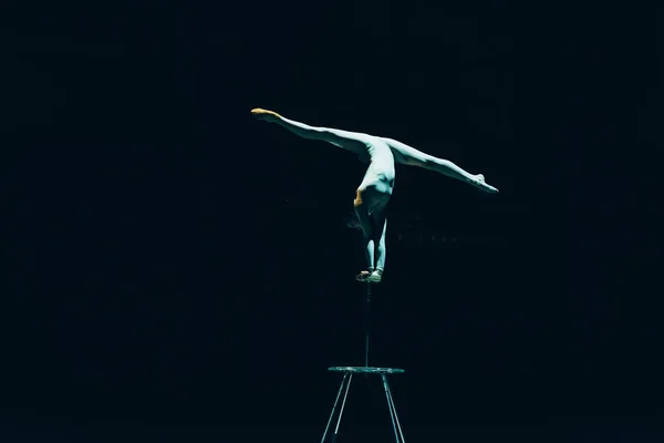 KYIV, UKRAINE - NOVEMBER 1, 2019: Female gymnast performing handstand and split in circus isolated on black — Stock Photo