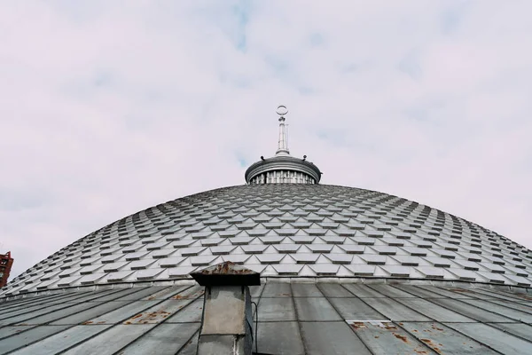 Vista ad angolo basso della guglia sul tetto dell'edificio con nuvole sullo sfondo — Foto stock