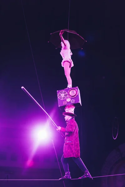 KYIV, UKRAINE - NOVEMBER 1, 2019: Low angle view of air gymnasts with umbrella and pole balancing on rope in circus — Stock Photo