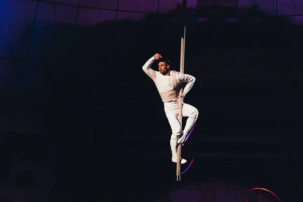 KYIV, UCRANIA - 1 DE NOVIEMBRE DE 2019: Guapo gimnasta de aire en el polo mirando hacia otro lado en circo aislado en negro - foto de stock