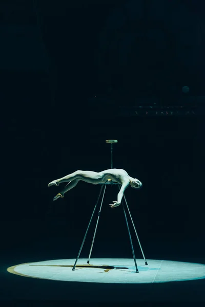 KYIV, UKRAINE - NOVEMBER 1, 2019: Side view of beautiful gymnast lying in spotlight in circus isolated on black — Stock Photo