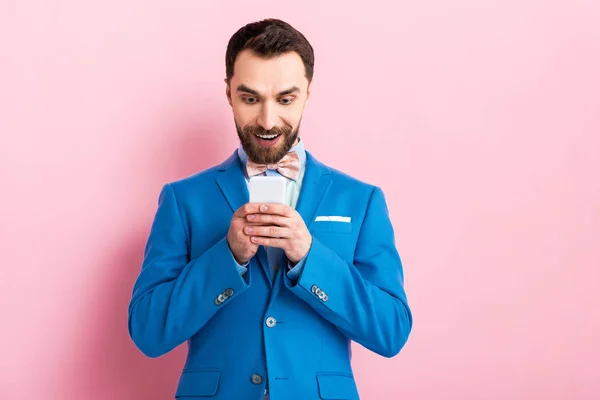 Cheerful businessman using smartphone on pink — Stock Photo