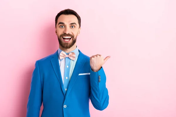 Happy bearded businessman pointing with finger on pink — Stock Photo
