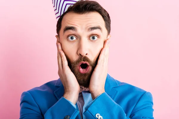 Shocked businessman touching face while looking at camera isolated on pink — Stock Photo