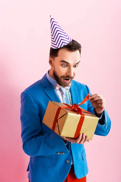 Sorprendido hombre de negocios en traje mirando al presente en rosa - foto de stock