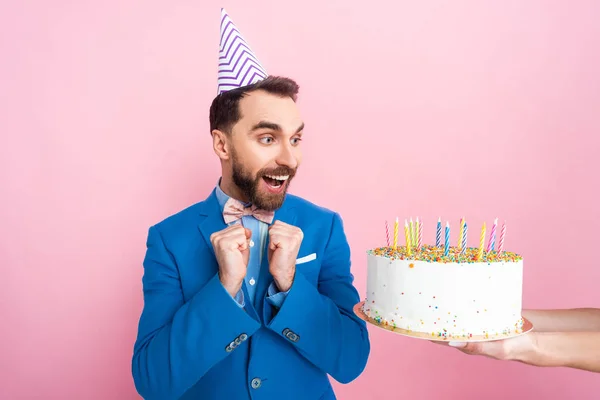 Recortado vista de la mujer de negocios celebración de pastel de cumpleaños cerca feliz hombre de negocios aislado en rosa - foto de stock