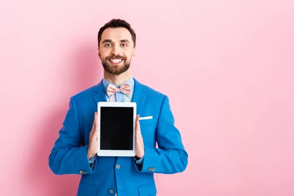 Счастливый бизнесмен держит цифровой планшет с чистым экраном на розовый — стоковое фото