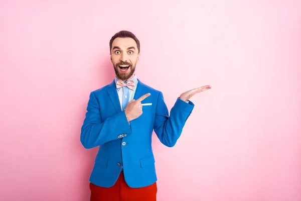 Aufgeregter Mann im Anzug zeigt mit Finger auf rosa — Stockfoto
