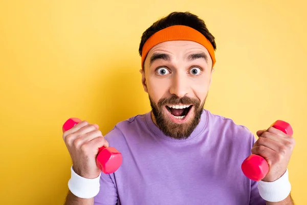 Desportista animado halterofilismo pequenos halteres rosa no amarelo — Fotografia de Stock
