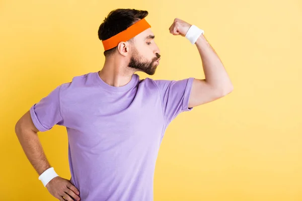 Seitenansicht des Sportlers Luftkuss auf Muskel isoliert auf gelb — Stockfoto