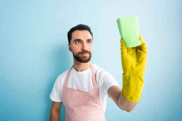 Selective focus of man looking at sponge on blue — Stock Photo