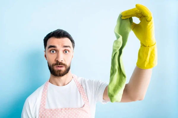 Selektiver Fokus eines schockierten Mannes mit schmutzigen Socken beim Putzen auf blau — Stockfoto