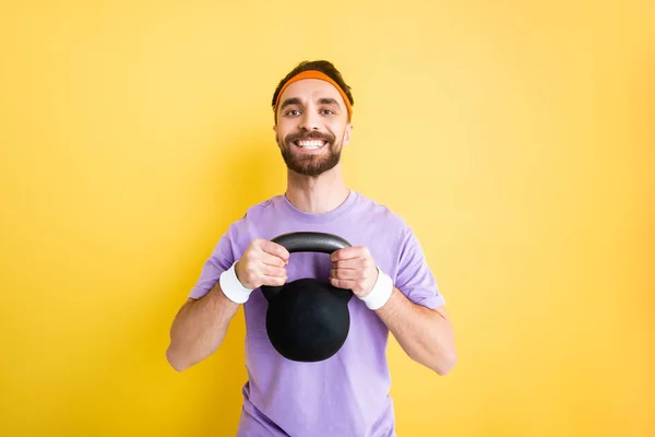 Desportista barbudo alegre exercitando com halteres pesados isolados no amarelo — Fotografia de Stock