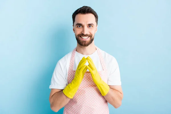 Hombre barbudo feliz en guantes de goma amarillos sonriendo en azul - foto de stock