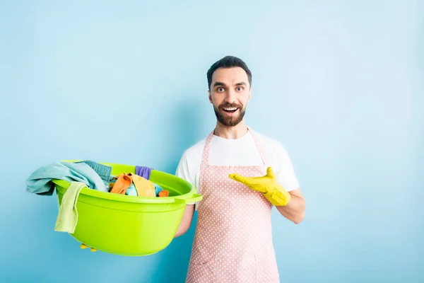 Positive bearded man pointing with hand at dirty laundry on blue — Stock Photo