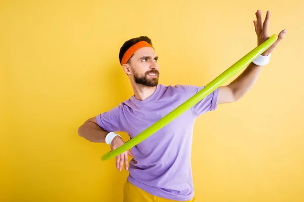 Confused sportsman working out with hula hoop isolated on yellow — Stock Photo