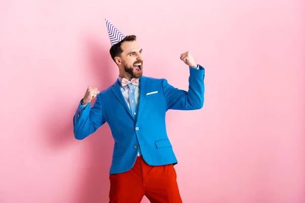 Felice uomo d'affari in berretto festa che celebra sul rosa — Foto stock