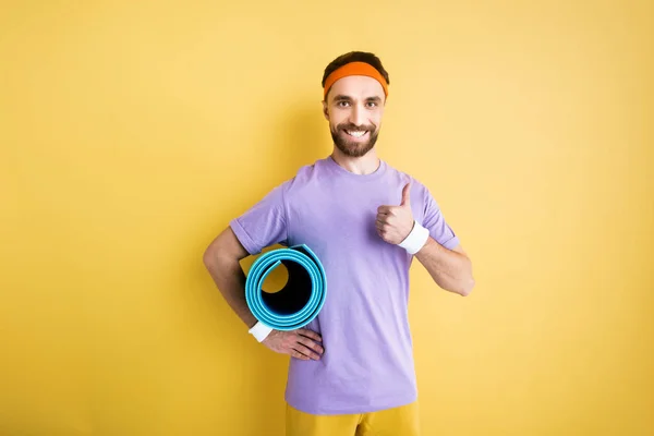 Cheerful bearded sportsman showing thumb up on yellow — Stock Photo