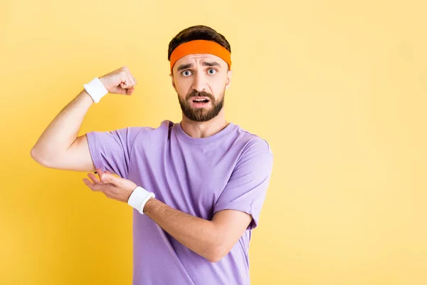 Bearded sportsman showing muscle isolated on yellow — Stock Photo