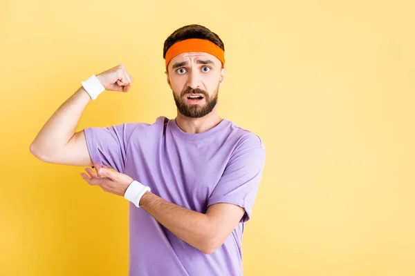 Barbuto sportivo mostrando muscolo isolato su giallo — Foto stock