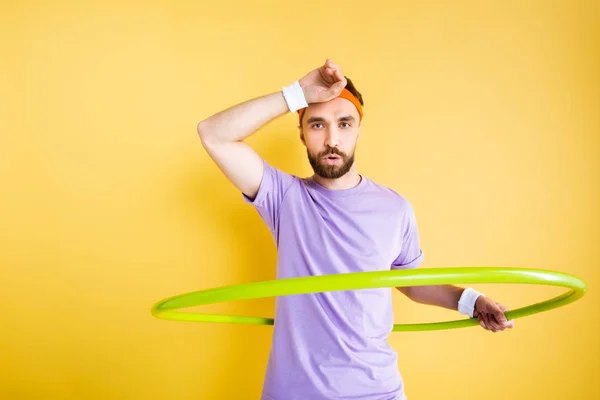 Tired sportsman working out with hula hoop on yellow — Stock Photo