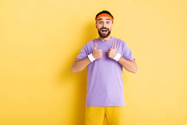 Alegre barbudo deportista mostrando pulgares hacia arriba en amarillo - foto de stock