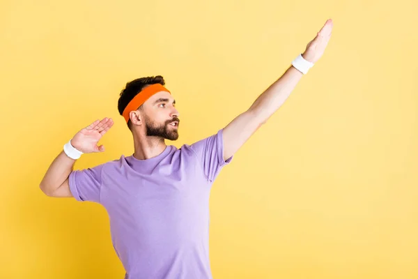 Bearded sportsman in headband gesturing isolated on yellow — Stock Photo