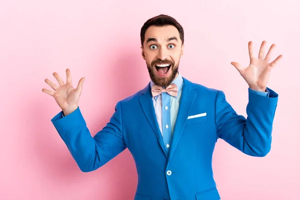 Hombre de negocios barbudo excitado con la boca abierta gestos en rosa - foto de stock