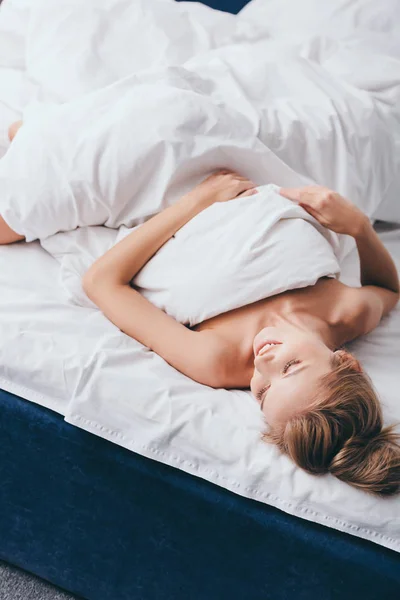 Красива усміхнена жінка лежить в ліжку вранці — стокове фото