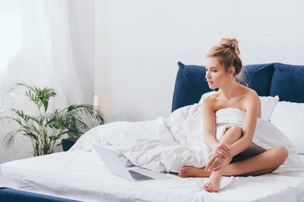 Hermosa mujer usando el ordenador portátil en la cama con sábanas en la mañana - foto de stock