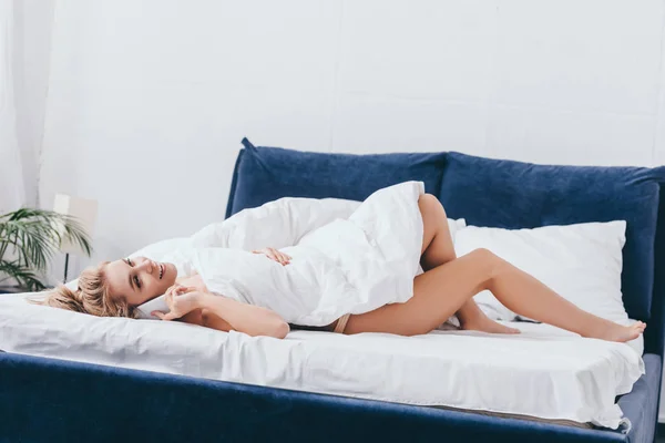 Schöne, glückliche Frau, die morgens im Bett auf dem Smartphone spricht — Stockfoto