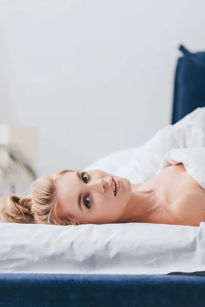 Attractive blonde woman lying on bed in morning — Stock Photo