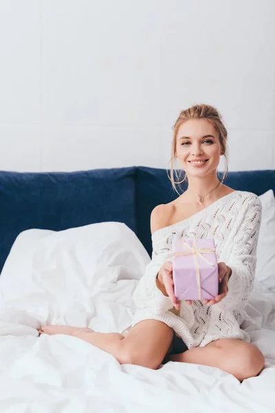 Allegra donna felice attraente che tiene la scatola regalo sul letto — Foto stock