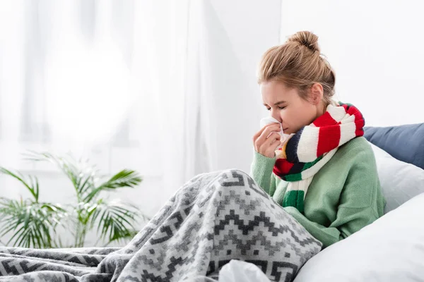 Triste mulher doente no cachecol ter corrimento nasal na cama com guardanapos — Fotografia de Stock