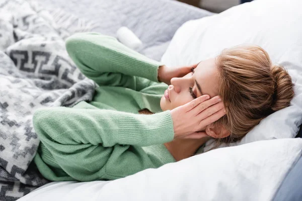Mujer cansada con dolor de cabeza y acostada en la cama por la mañana — Stock Photo