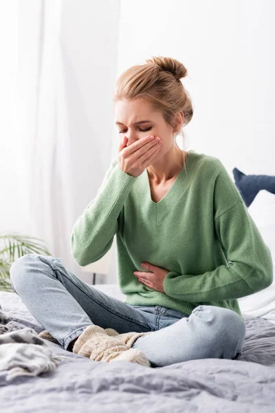 Bella donna con nausea e seduta sul letto — Foto stock