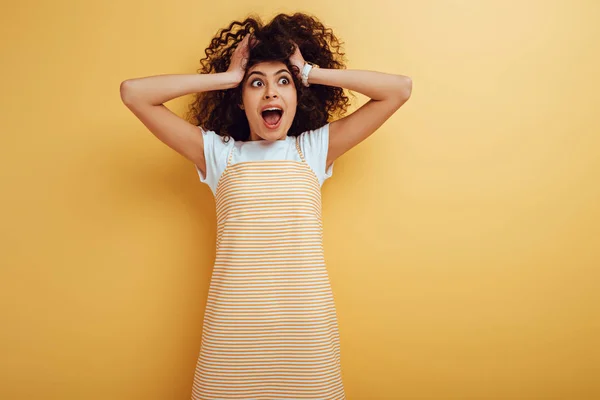 Scioccato misto razza ragazza toccare la testa e guardando lontano su sfondo giallo — Foto stock