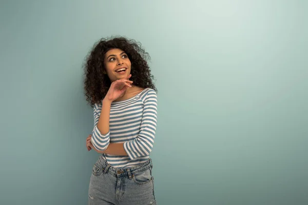 Happy bi-racial girl smiling while looking away on grey background — Stock Photo