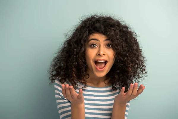 Irritated mixed race girl shouting at camera and showing indignation gesture on grey background — Stock Photo