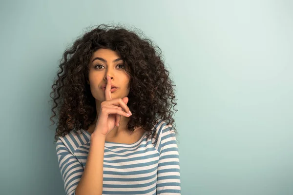 Jolie fille de race mixte montrant geste de silence tout en regardant la caméra sur fond gris — Photo de stock