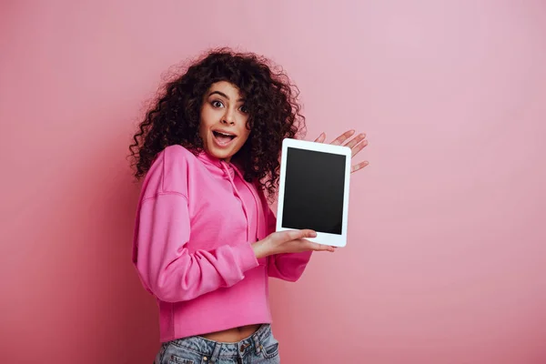 Schockiertes Mädchen mit gemischter Rasse zeigt Smartphone mit leerem Bildschirm auf rosa Hintergrund — Stockfoto