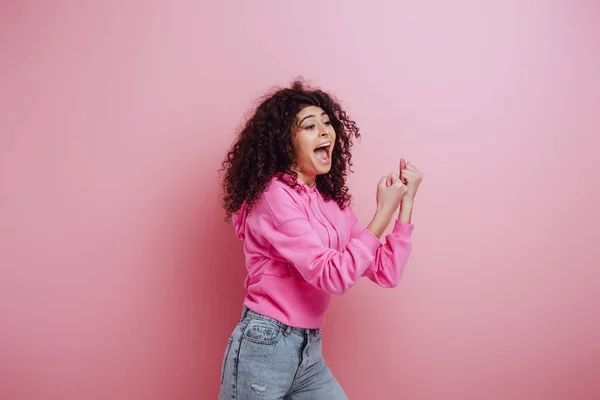 Eccitato bi-razziale ragazza gridando mentre mostra il gesto vincitore su sfondo rosa — Foto stock