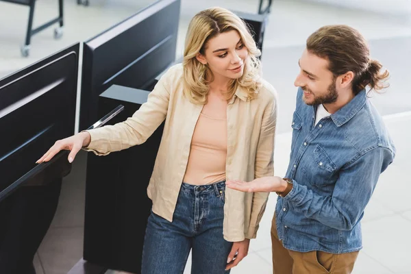 Hochwinkelaufnahme eines lächelnden Freundes, der mit der Hand auf den neuen Fernseher zeigt und mit seiner Freundin im Haushaltsgerätegeschäft spricht — Stockfoto