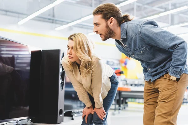 Freund und Freundin schauen sich neuen Fernseher im Haushaltsgerätegeschäft an — Stockfoto