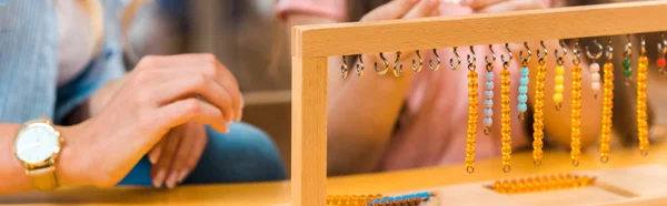 Vista ritagliata del gioco educativo da insegnante e bambino nella scuola montessori, scatto panoramico — Foto stock